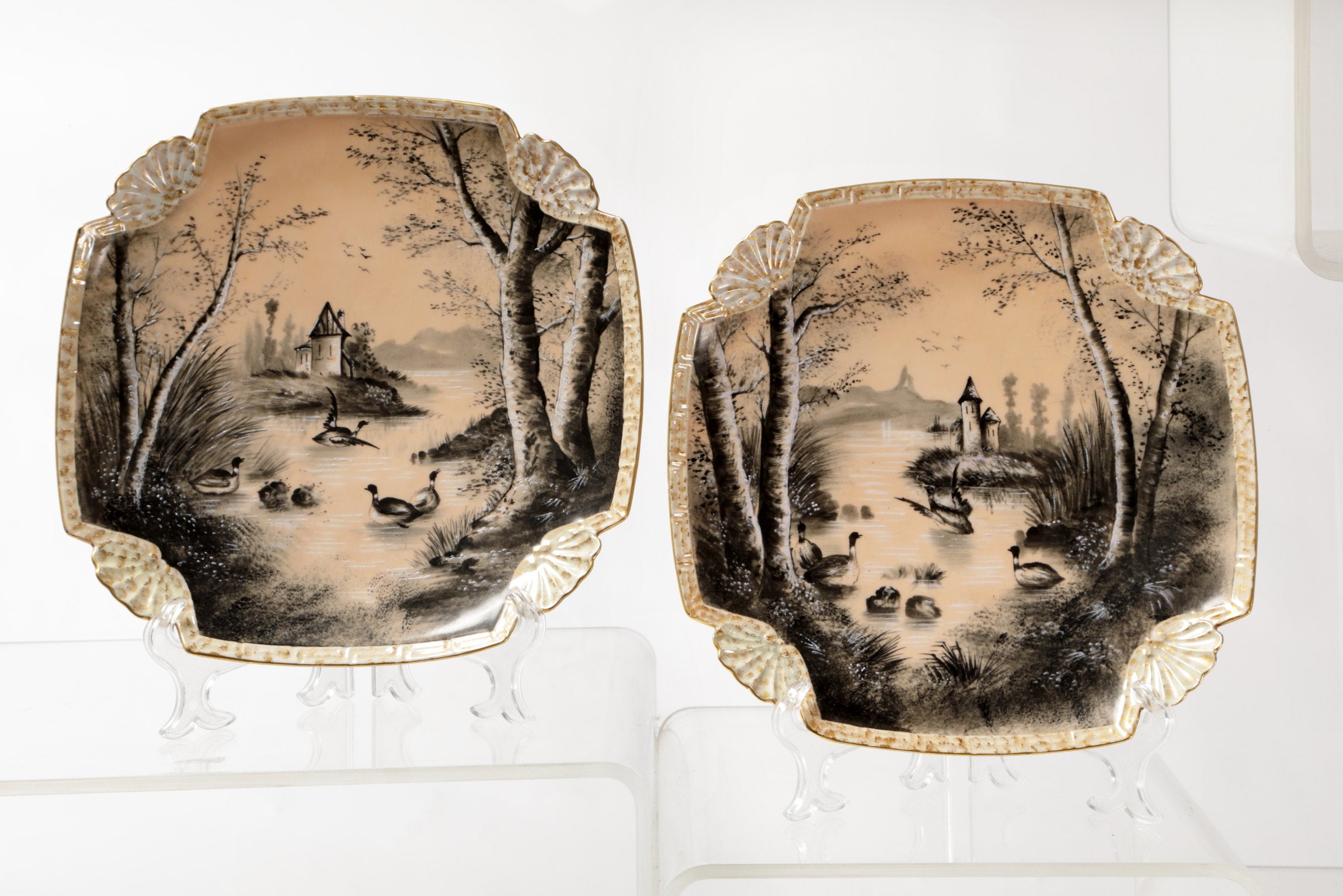 Pair of porcelain plates with lake scene and powder pink background