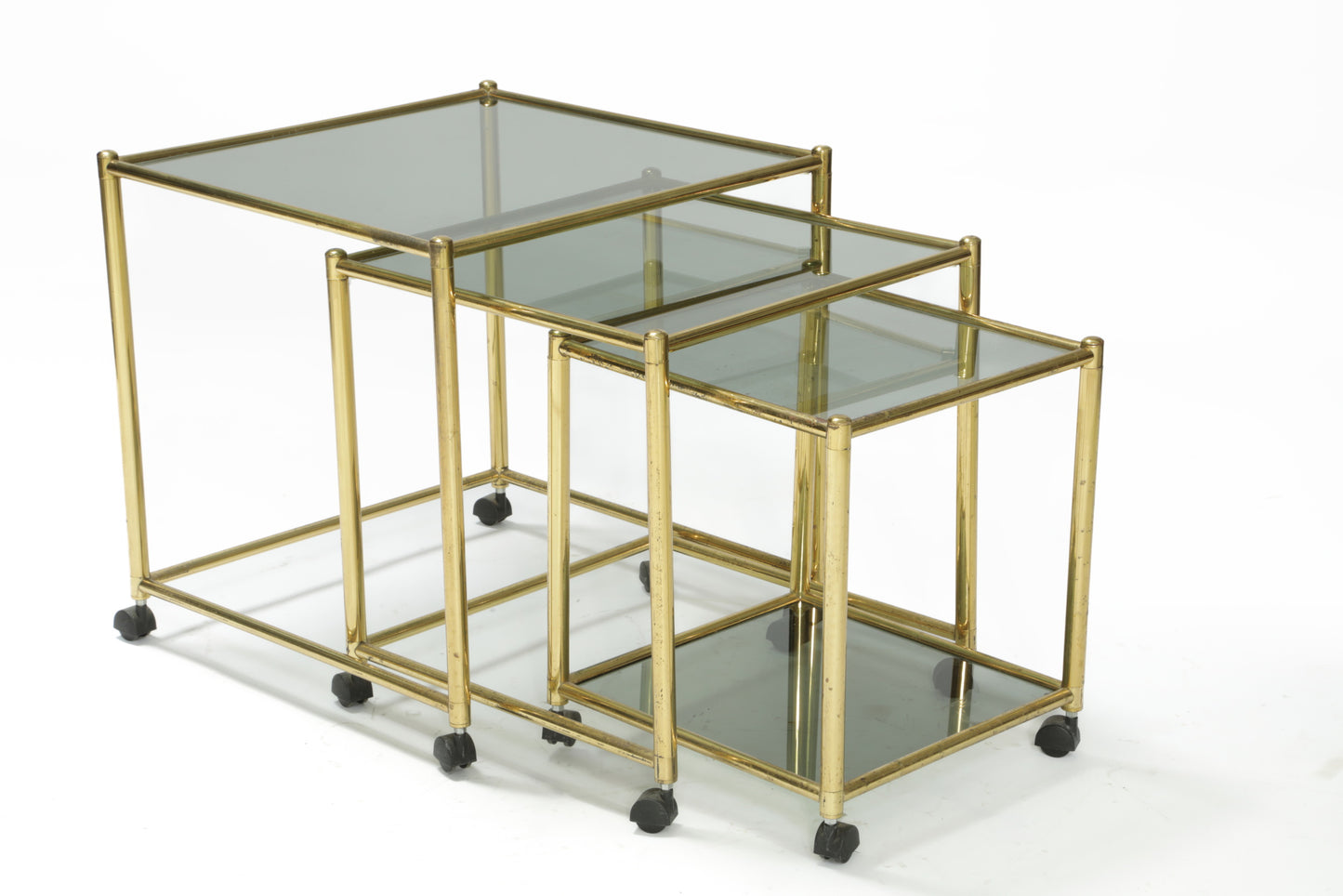 Triptych of brass and smoked glass tables from the 70s