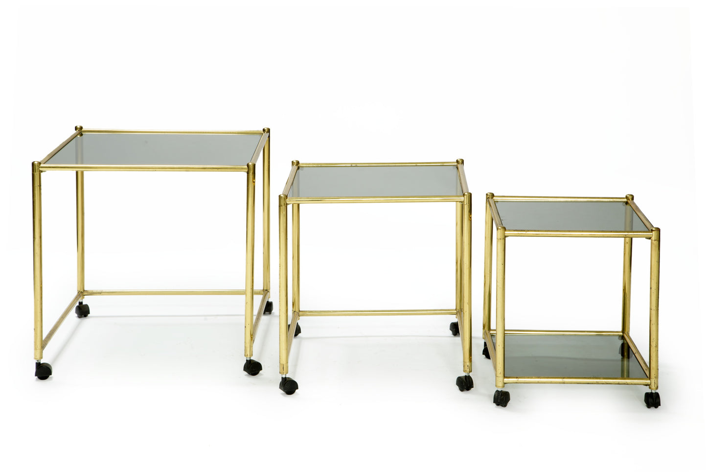 Triptych of brass and smoked glass tables from the 70s